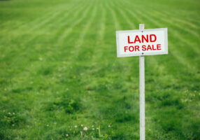 land for sale sign against trimmed lawn background
