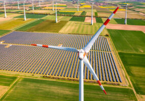 Huge wind turbines between agricultural land and a solar park in a rural area from a drone perspective, Germany