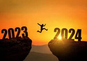 Man jumping on cliff 2024 over the precipice at amazing sunset. New Year's concept. Symbol of starting and welcome happy new year 2024. People enters the year 2024, creative idea